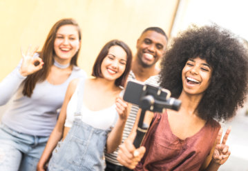 Millennial people taking video selfie with stabilized mobile phone